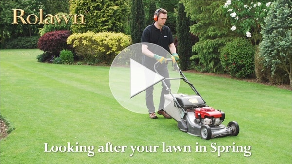 Opening frame of Rolawn's Spring lawn care video showing a lawn being mowed with a video play button overlaid